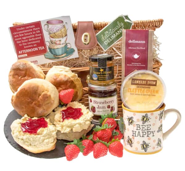 A basket filled with scones, jam, clotted cream, tea and a jar of Devon honey with a cute bee mug.