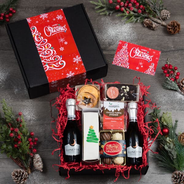 A christmas gift box with a red festive banner containing 2 mini bottles of Prosecco, an iced christmas fruit cake, 2 mince pies, chocolate truffles and christmas fudge.