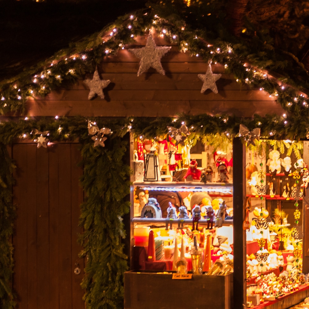 A rustic wooden shack adorned with twinkling christmas lights, offering a unique and enchanting experience for visitors exploring Devon this Summer.