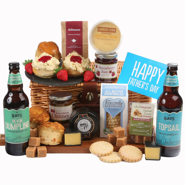 A variety of gourmet food items including cheeses, fudge, chutney, clotted cream, and beer bottles, arranged around a Dad's Afternoon Tea With Cheese, Chutney & Beer Hamper.