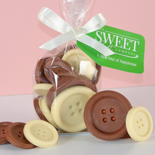 A clear bag containing approximately 120g of Milk & White Chocolate Buttons, tied with a white ribbon and adorned with a green tag labeled "Sweet Company.